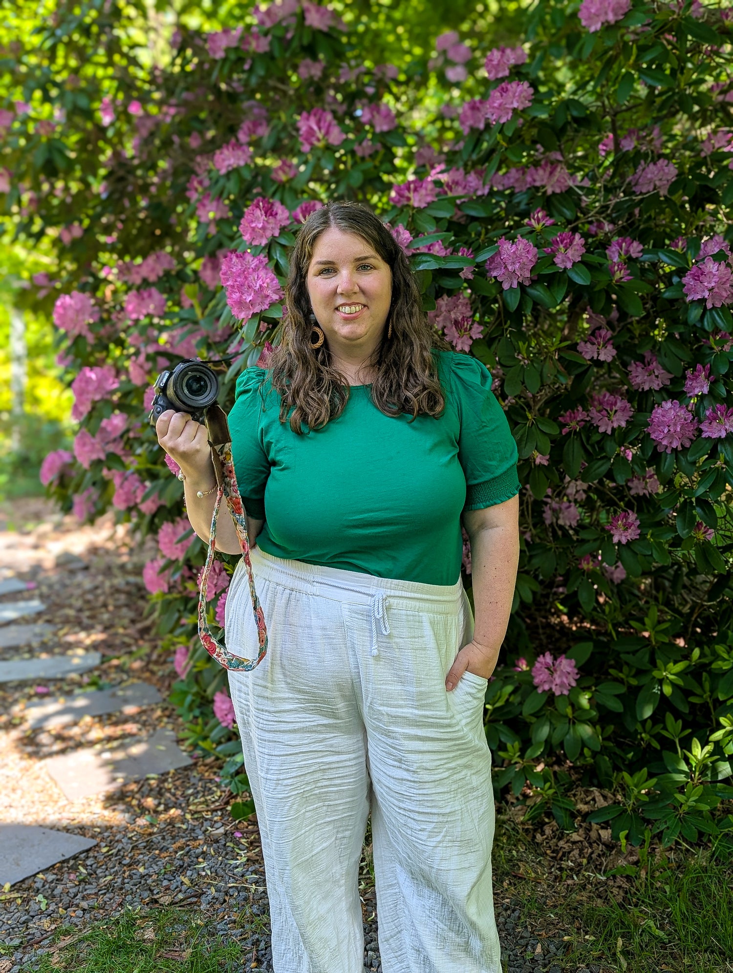 Woman holding a camera in front of pink flowers
